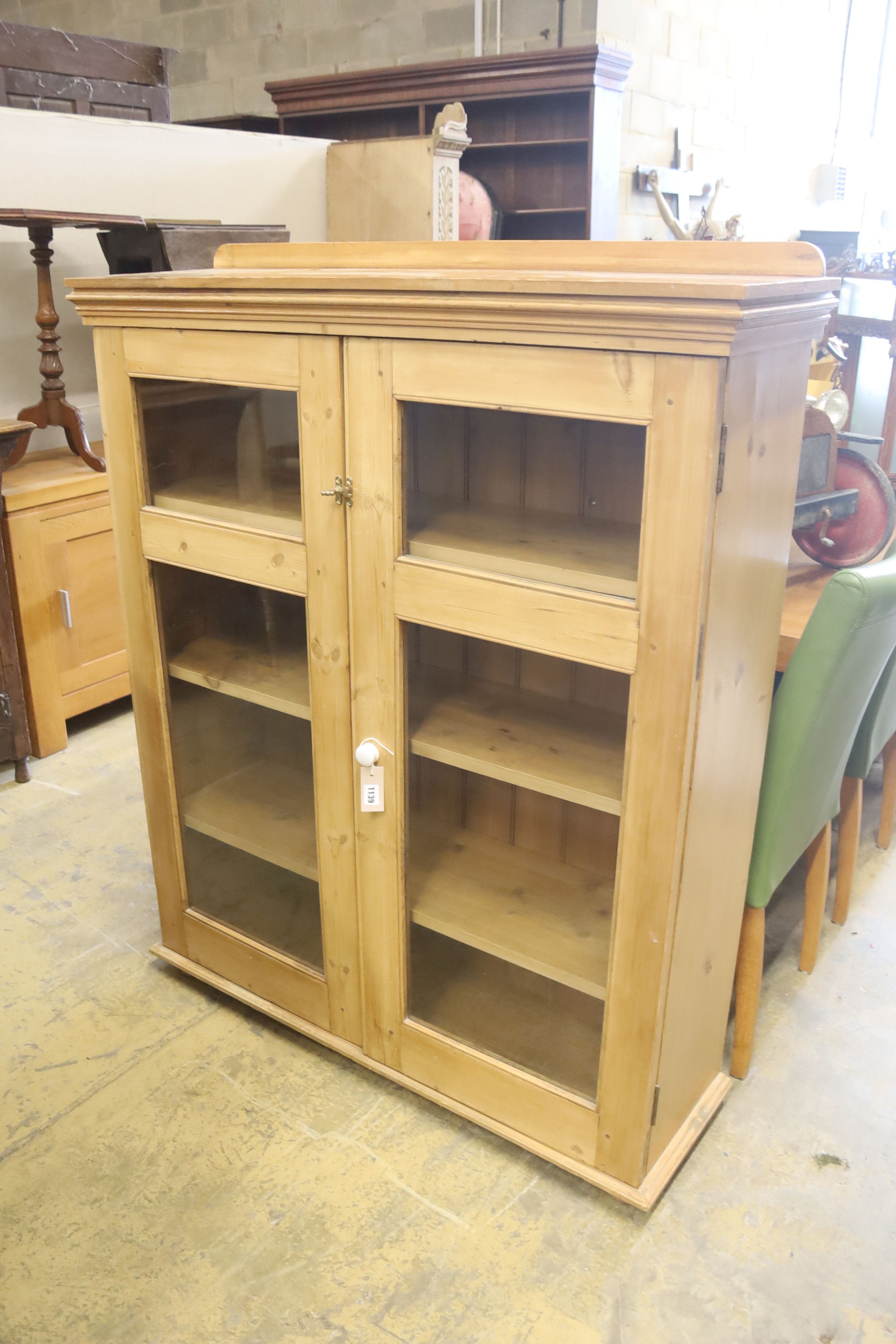 A modern glazed pine bookcase fitted two doors and shelves, length 114cm, depth 34cm, height 140cm